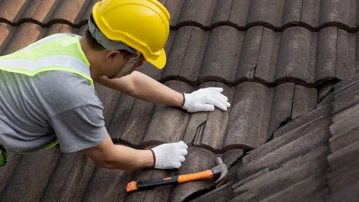 Roofer repairing damaged roof tiles during an emergency call-out